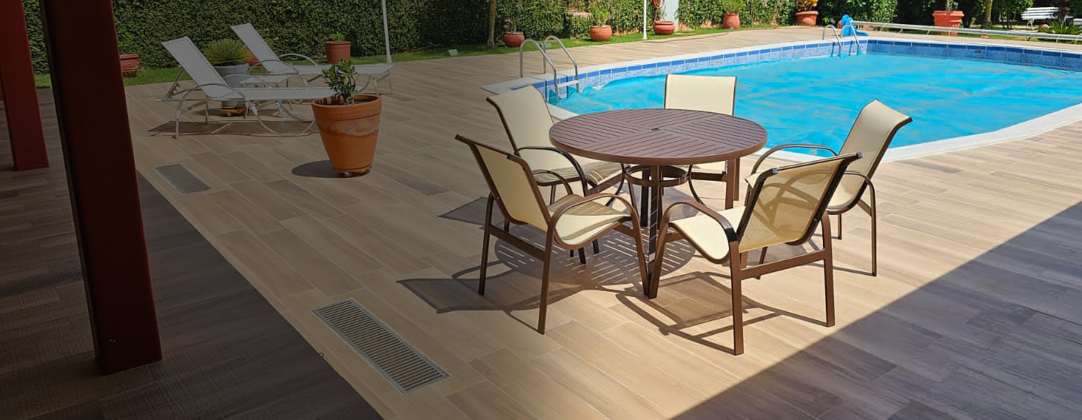 Conjunto de mesa ripada em aluminio e cadeiras em tela sling proximo a piscina